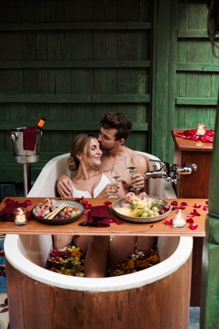 a person and person in a bathtub with food and flowers.