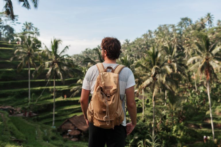 a person standing on a hill with a backpack.